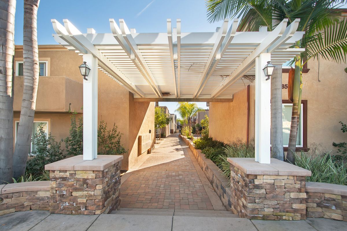 a white pergola over a walkway leading to a building