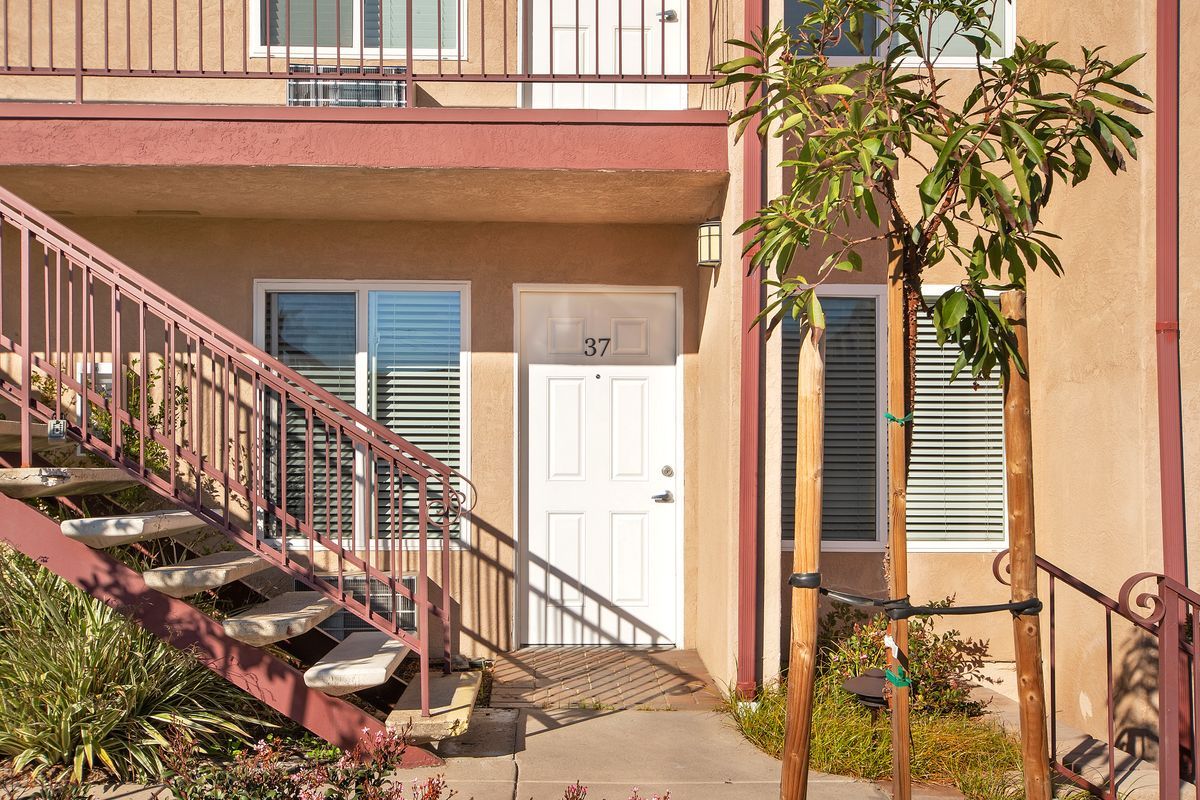 a building with stairs leading up to the front door and a tree in front of it .