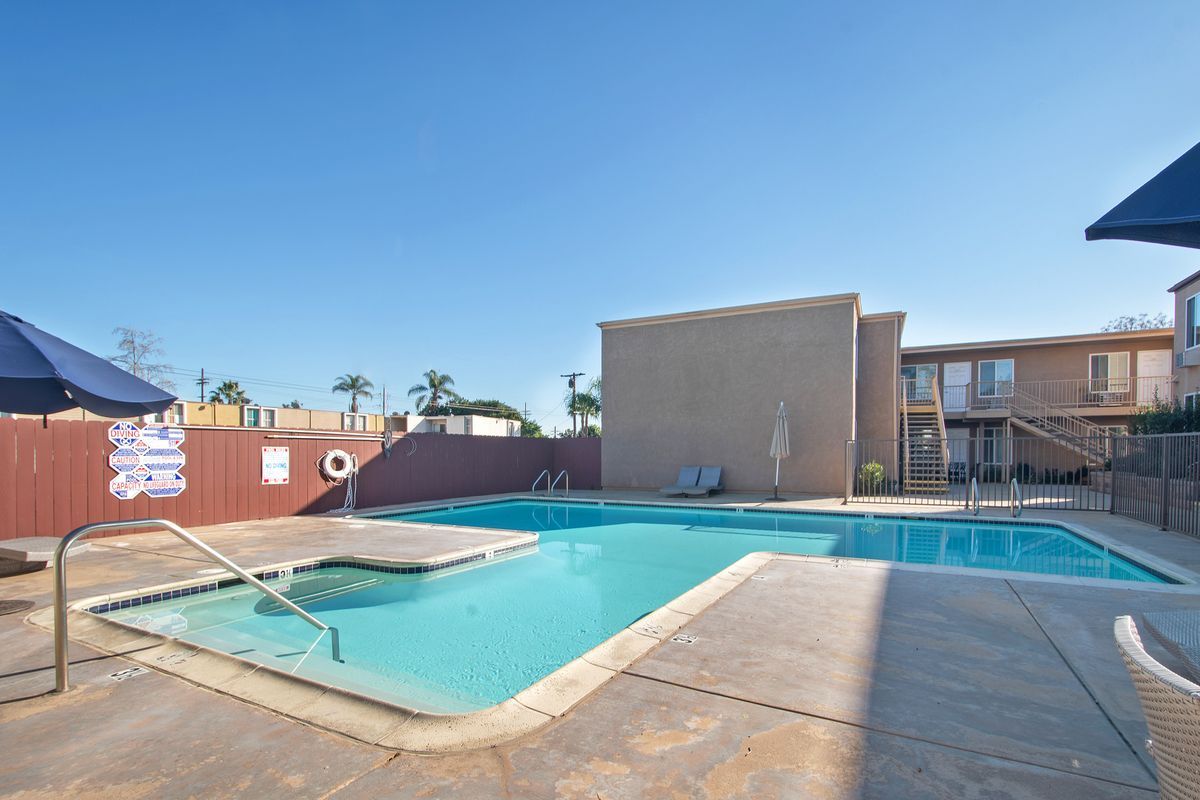 a large swimming pool with umbrellas in front of a building .