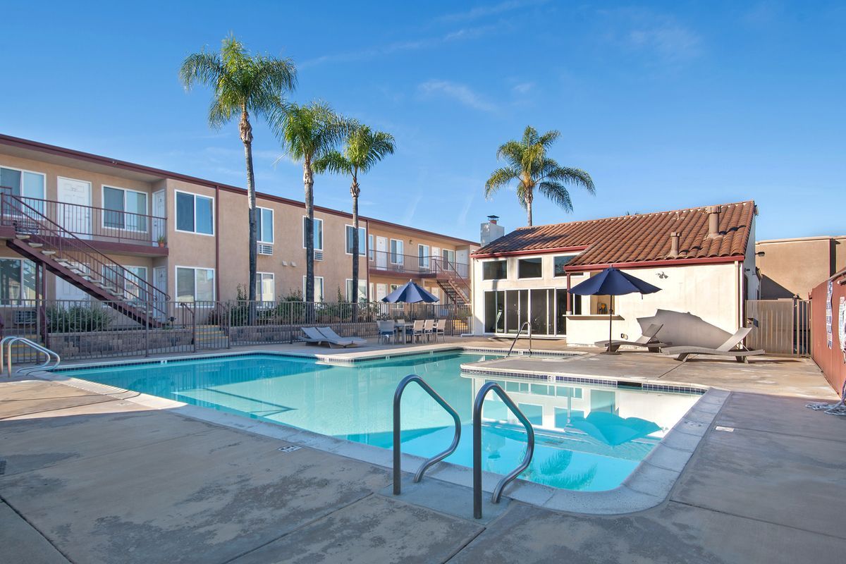 a large swimming pool in front of a building with palm trees .