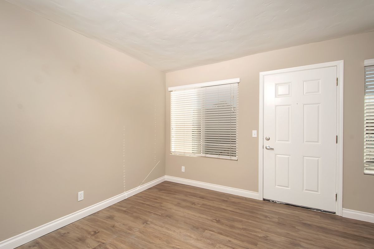 an empty room with hardwood floors , two windows and a door .