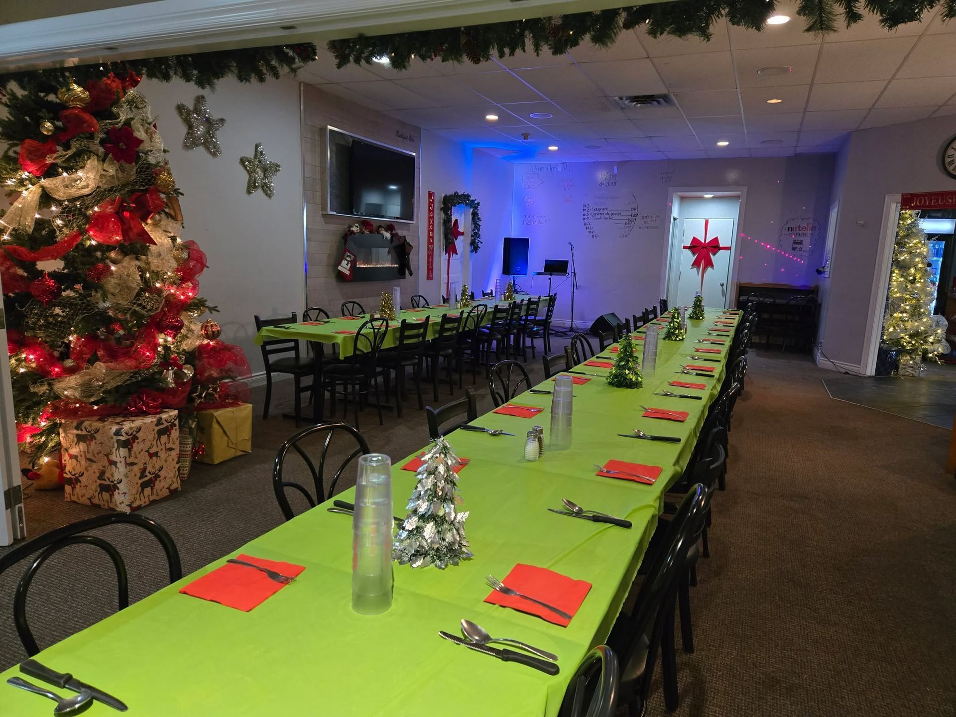 Une salle à manger décorée et festive, avec une longue table recouverte d'une nappe vert citron, dressée pour un repas de fête.