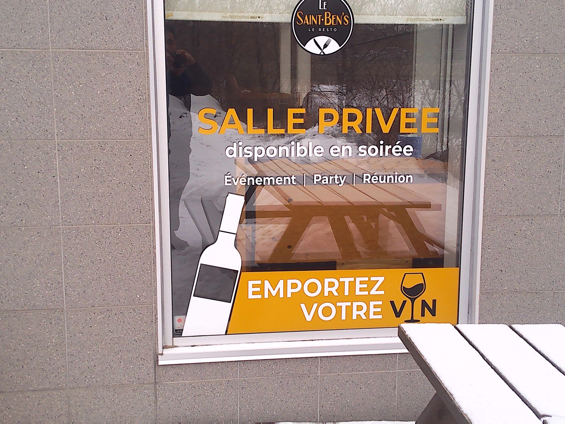Une vitrine avec des panneaux en français proposant une salle privée pour les événements et encourageant à « apporter son propre vin ».