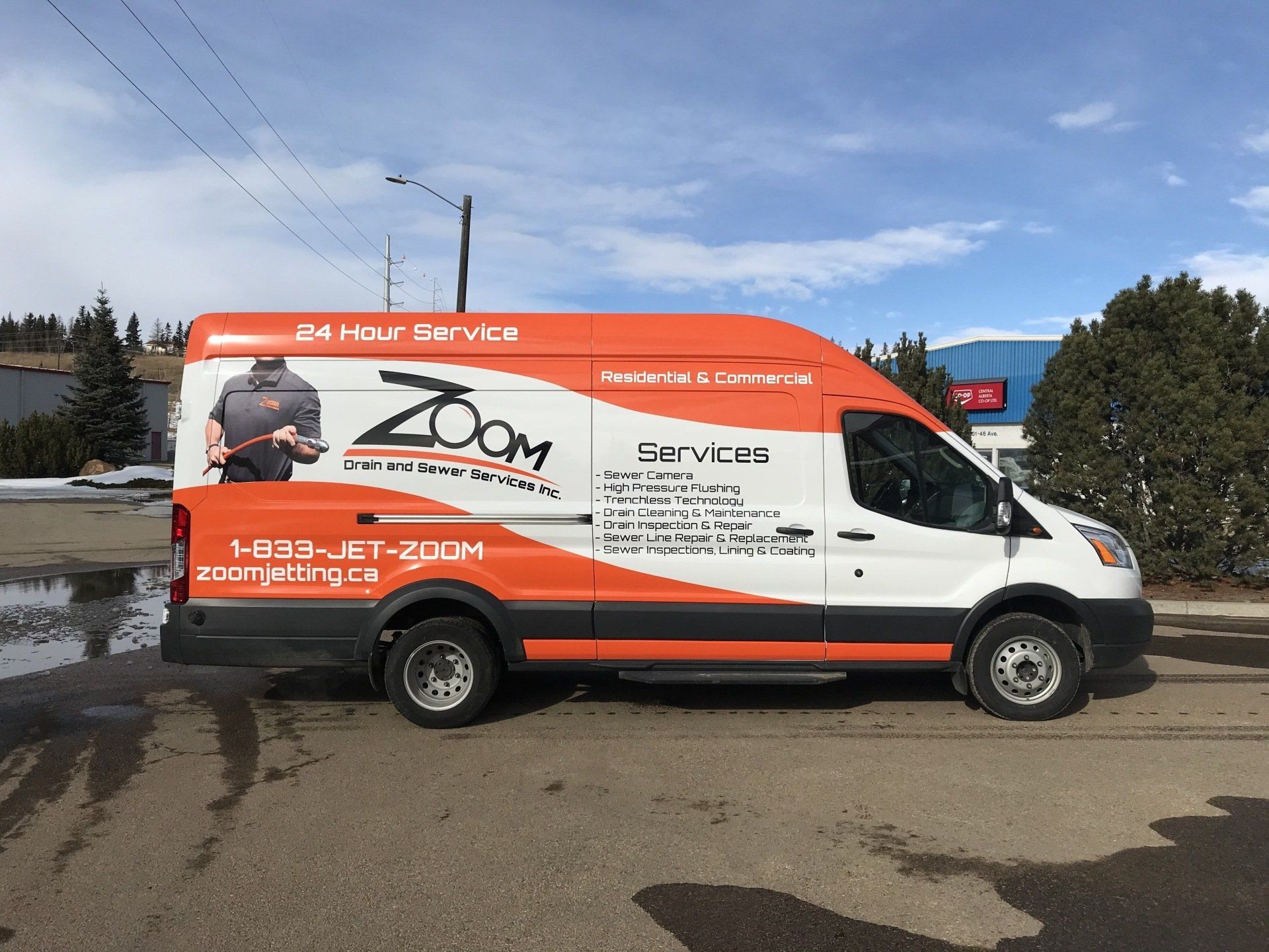 Orange and white Zoom Services van parked on a street with text and logo displayed.