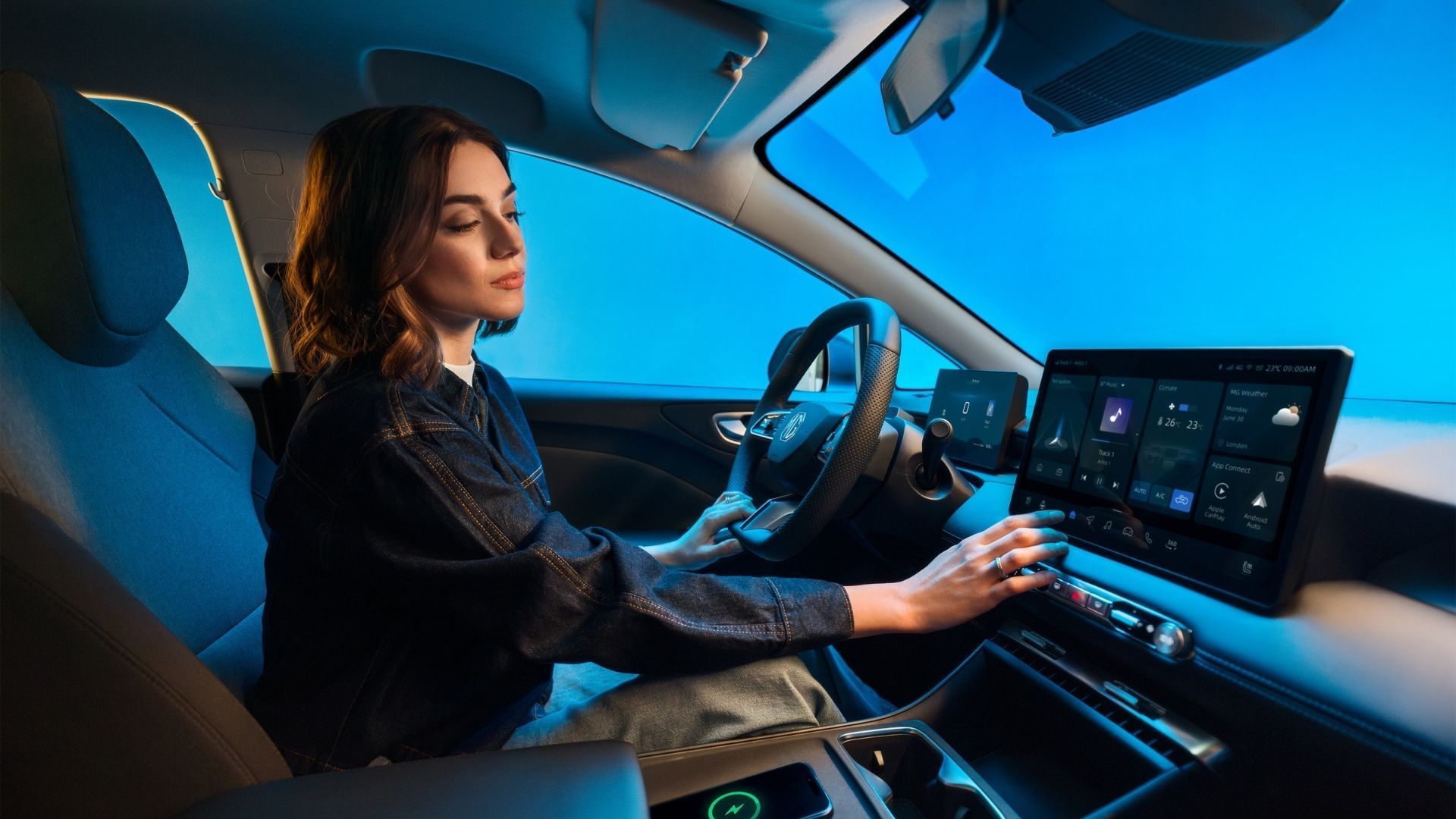 Woman driving a car at night, using a digital dashboard and touch display.
