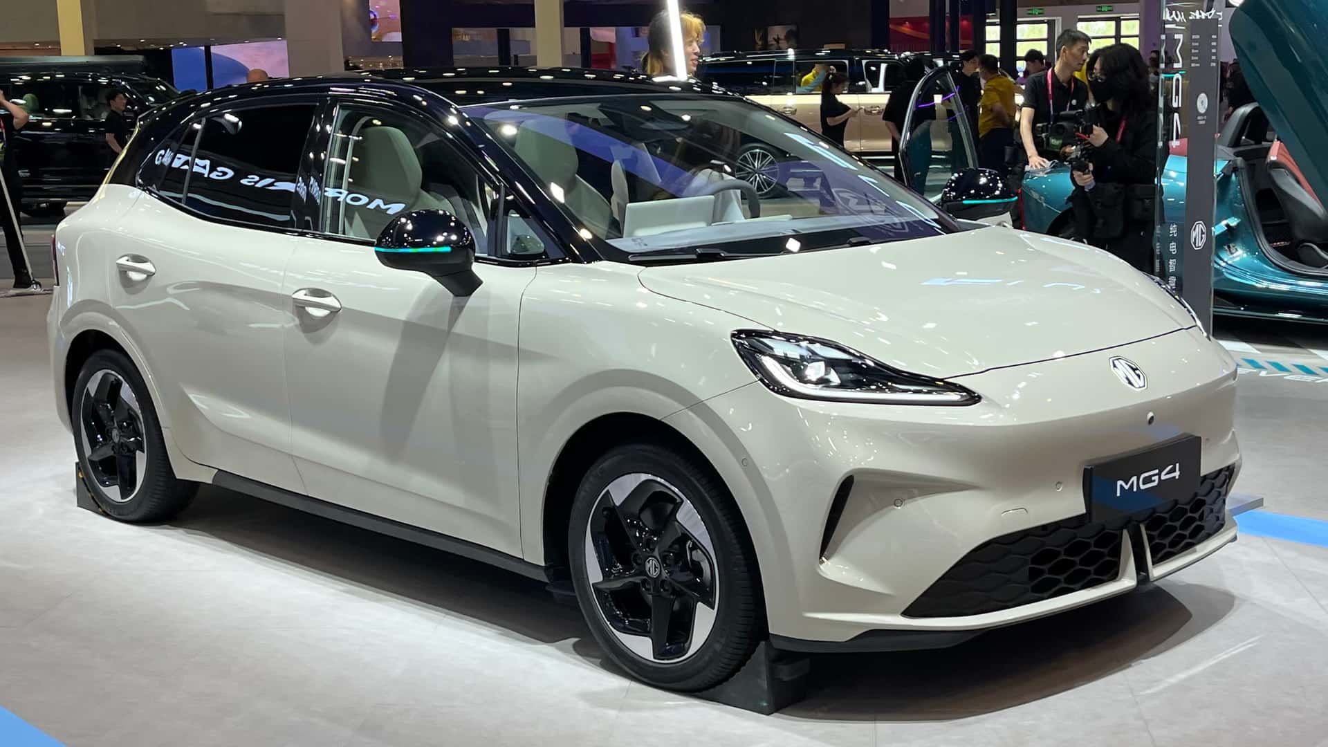 White compact electric SUV on display at an auto show, viewed from the front-left side.