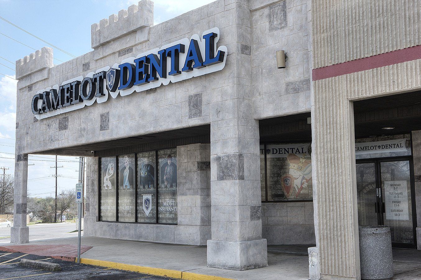 Exterior of a dental clinic storefront with a large sign and windows on a gray building
