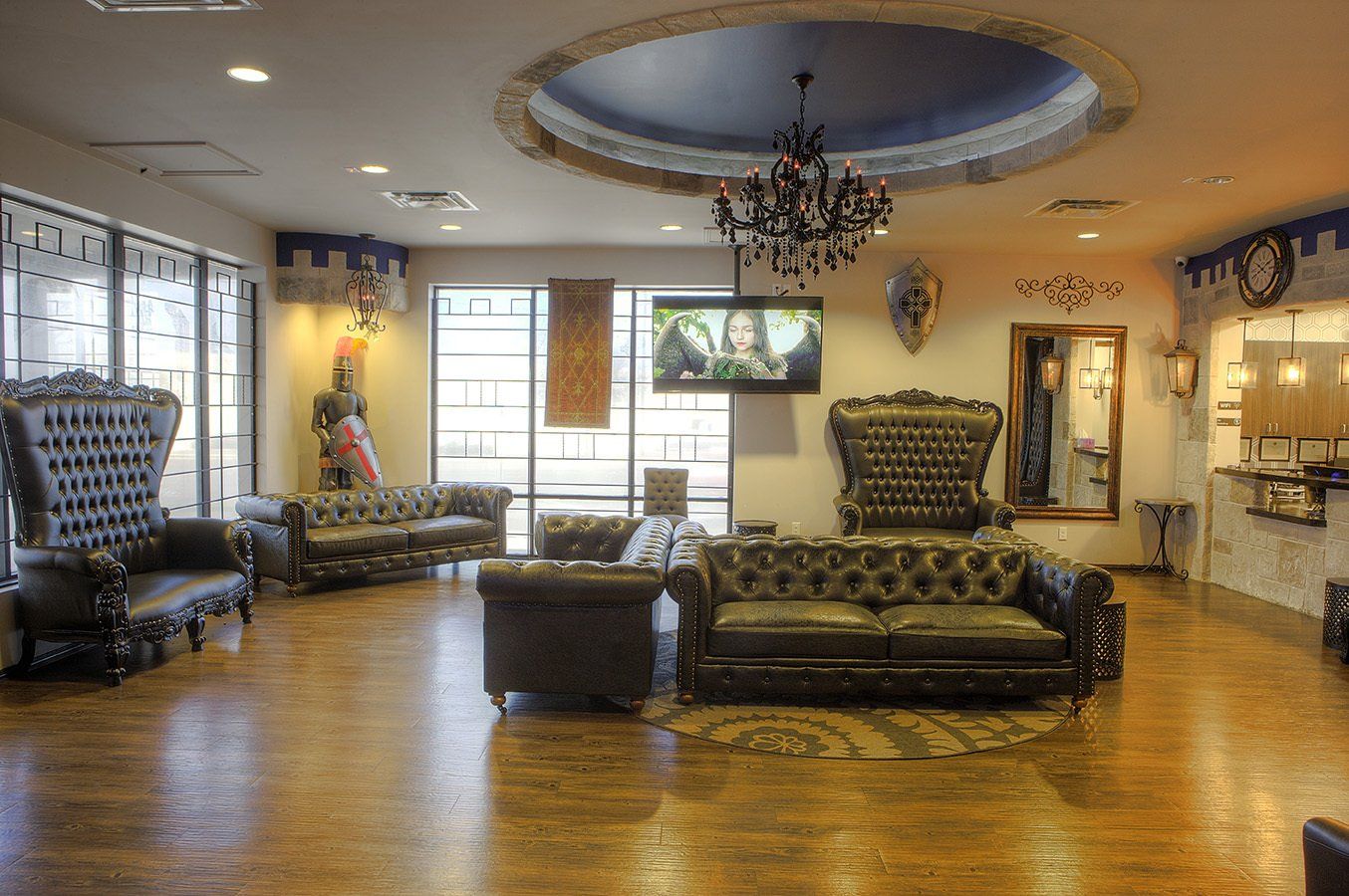 Spacious lobby with ornate gold chairs, a chandelier, wood floors, and large windows.