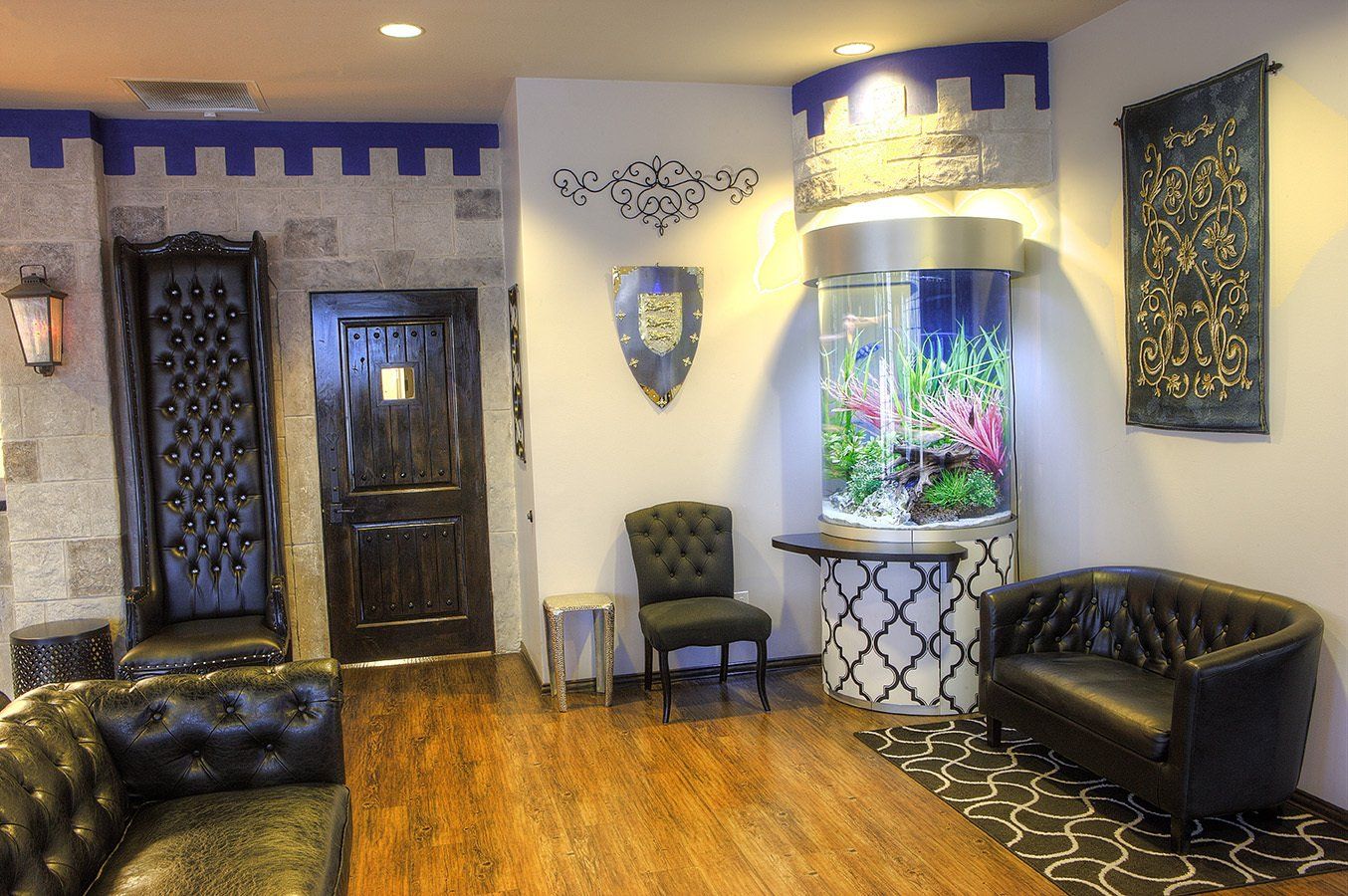 Lobby with purple accents, dark leather seating, wood floor, and a lit wall aquarium centerpiece