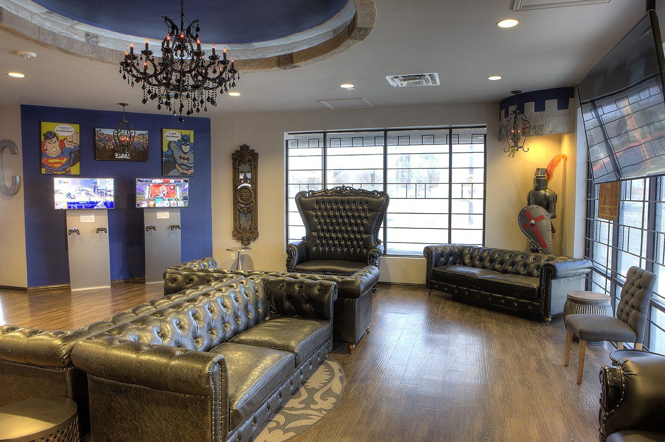 Modern lobby with black leather seating, TV wall, chandelier, and large window seating area