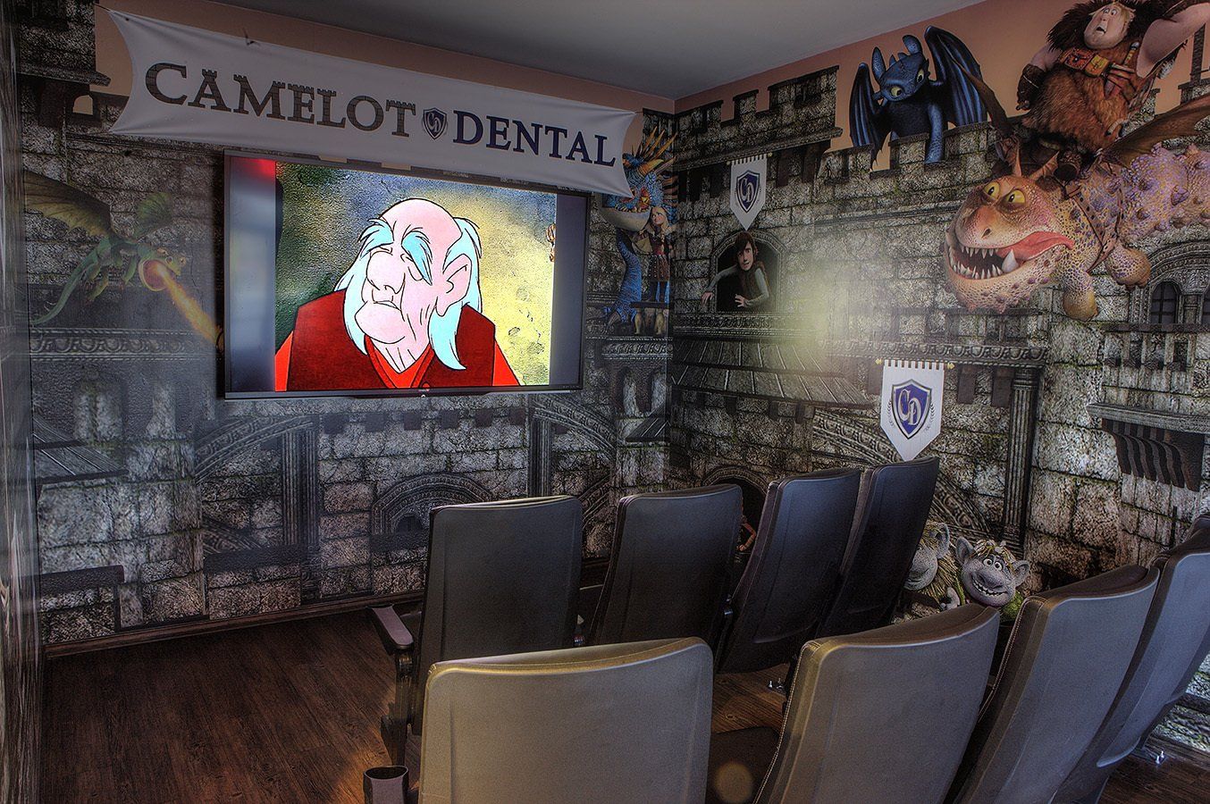 Dentist waiting room with a TV on the wall and several dark chairs facing it