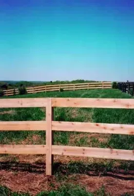 Wooden fence across a grassy field under a bright blue sky