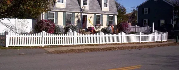 House with white picket fence and flower boxes along a street on a sunny day