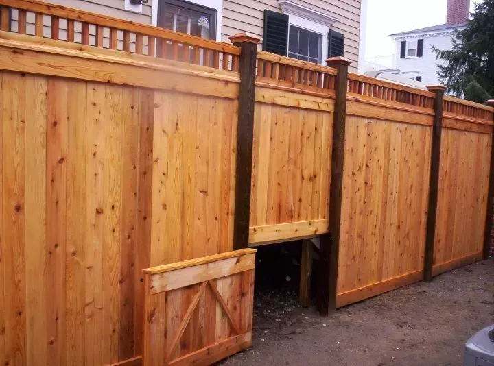 Wooden fence with a gate and small opening in a residential alley
