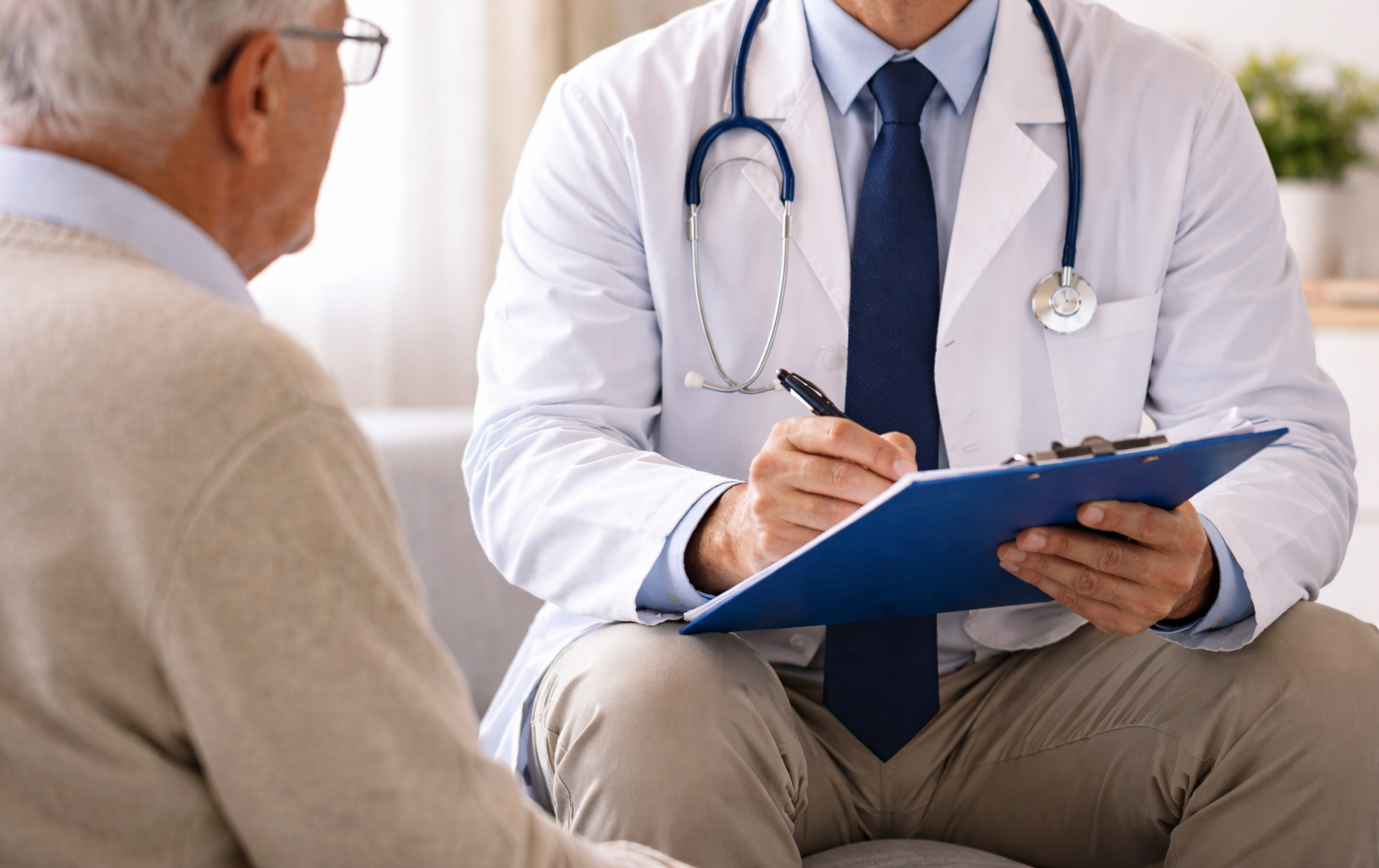 Doctor taking notes during a consultation with a seated patient