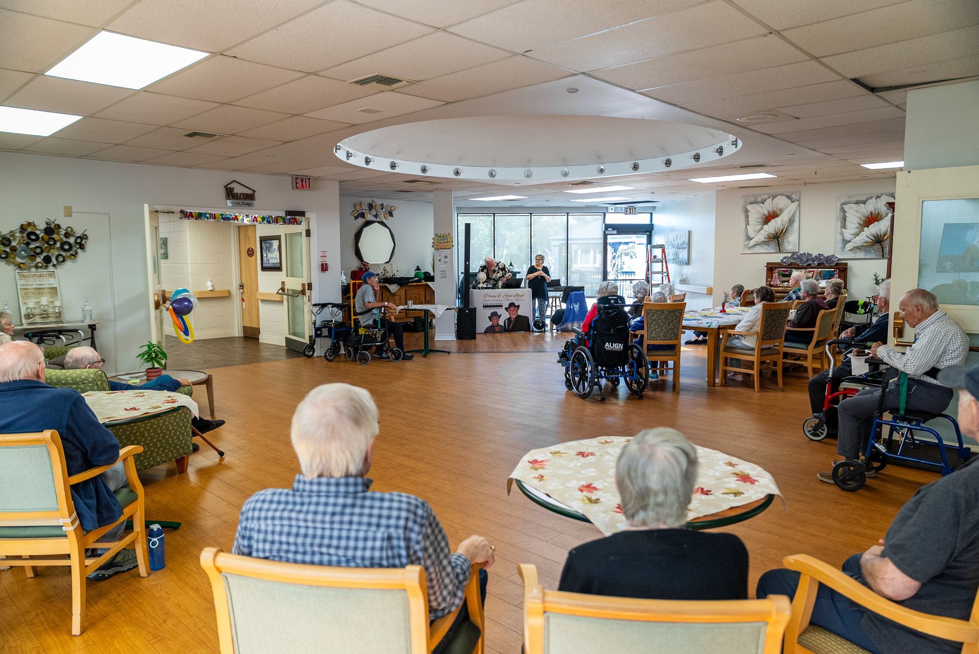 Residents seated in a bright common room, gathered around a spacious central activity area.