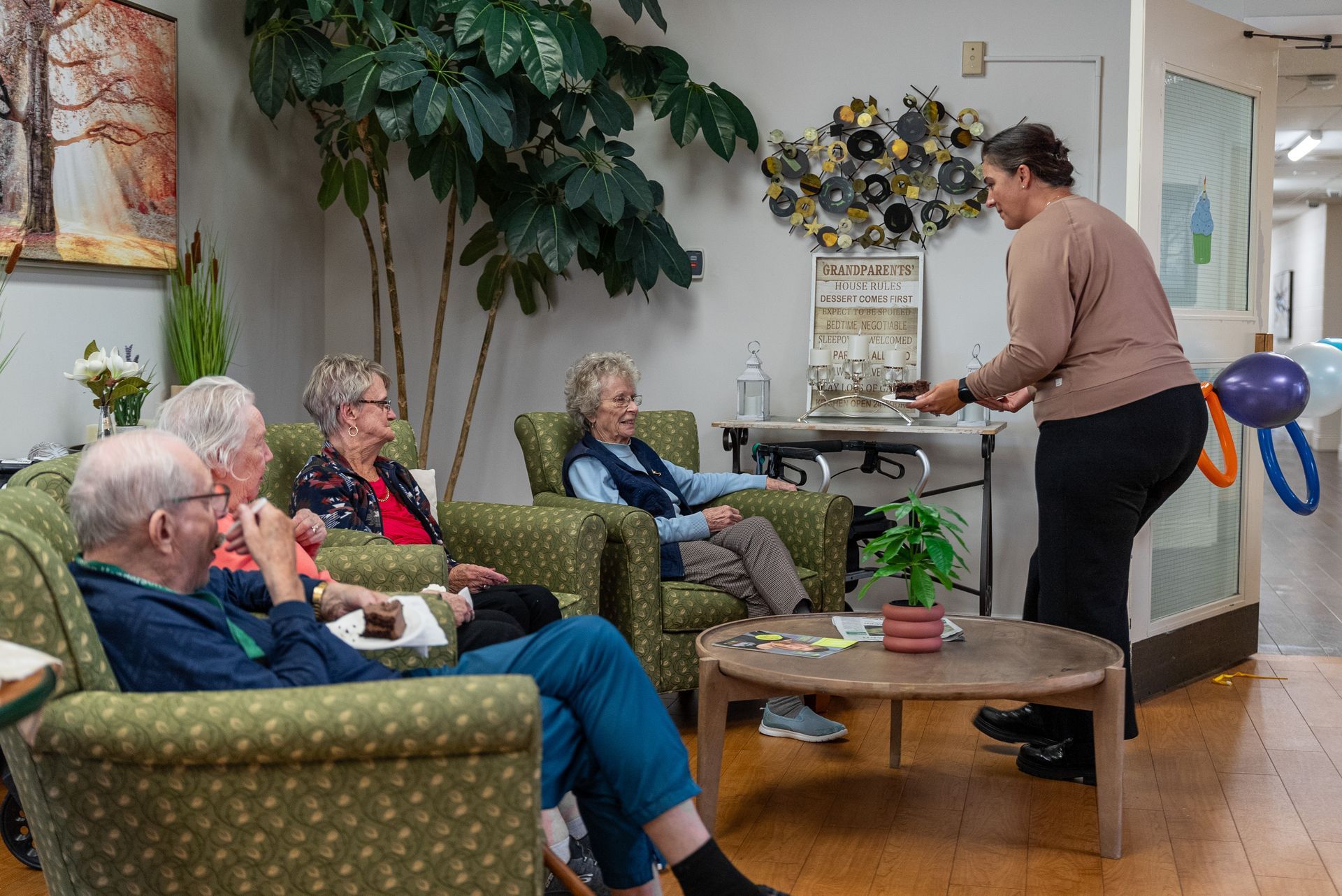 Group seated in a cozy room while a person presents beside a table and wall display