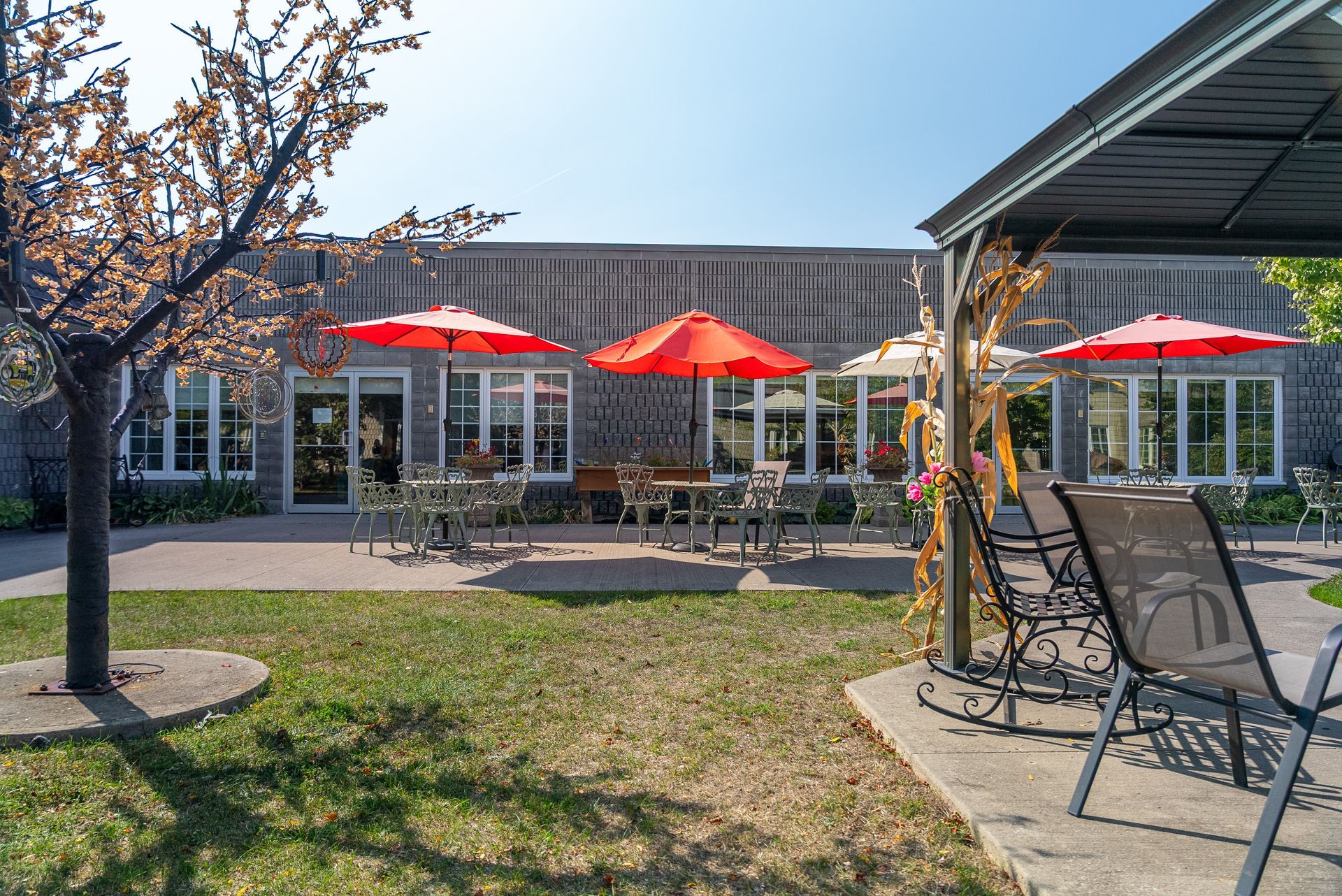 Patio with red umbrellas, chairs, and a building in the background on a sunny day