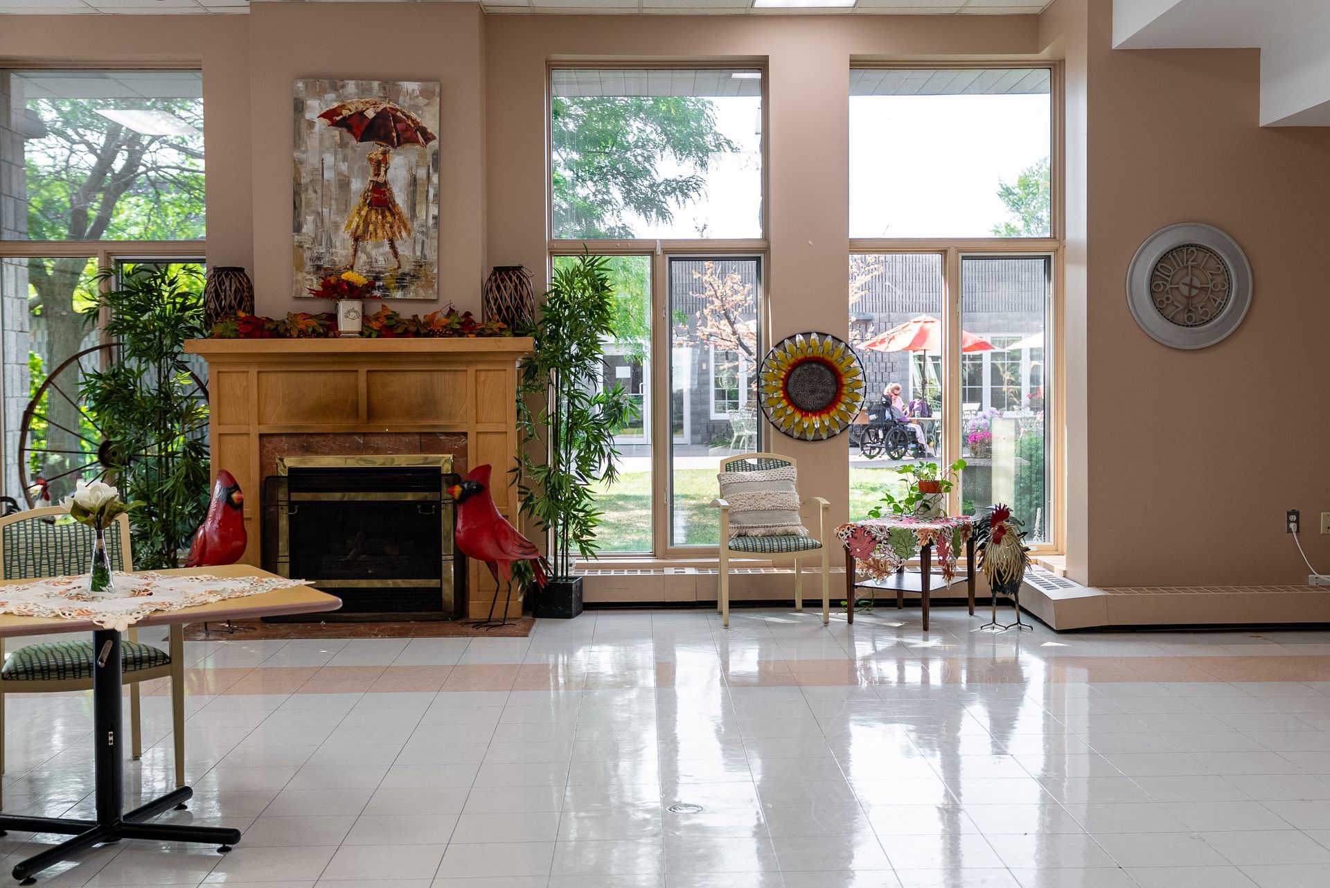 Bright lobby with a fireplace, large windows, and polished floor; chairs and decor near the entrance.