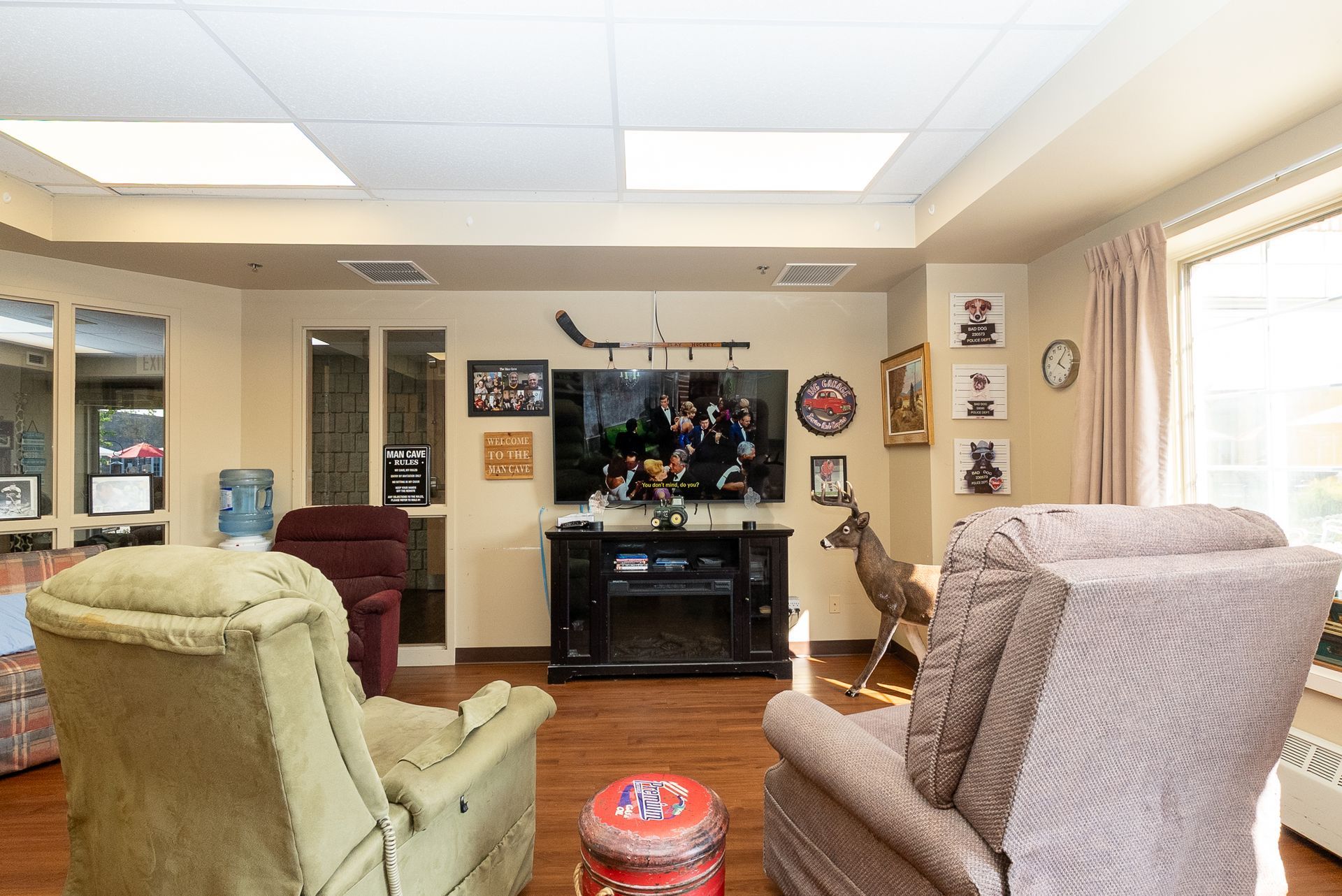 Living room with TV, beige recliners, curtains, and a deer statue near the entertainment center