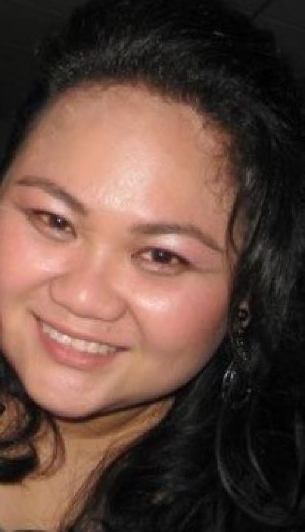 Close-up portrait of a smiling woman with dark hair against a dark background