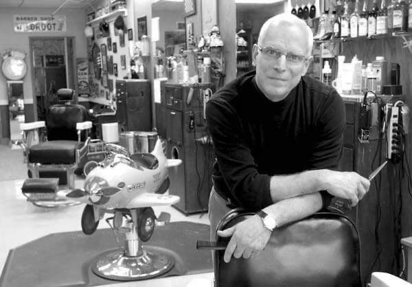 A man leaning on a chair in a barber shop