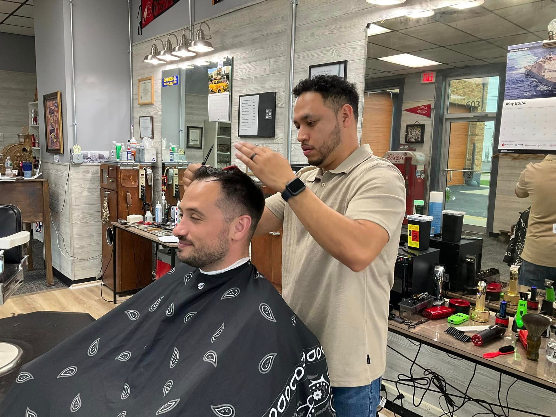 A man is getting his hair cut by a barber in a barber shop.