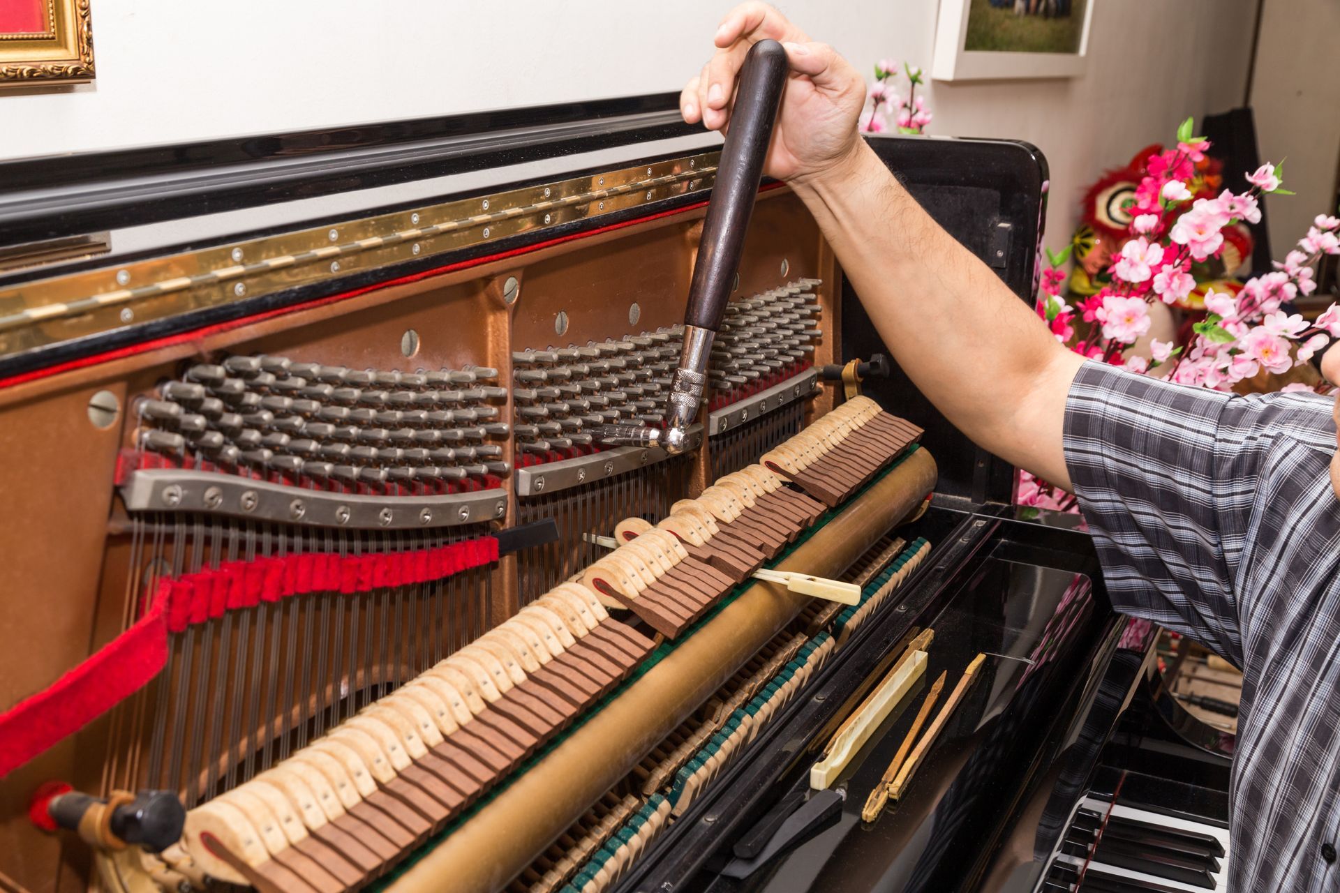 Piano tuning technician adjusting strings inside an upright piano