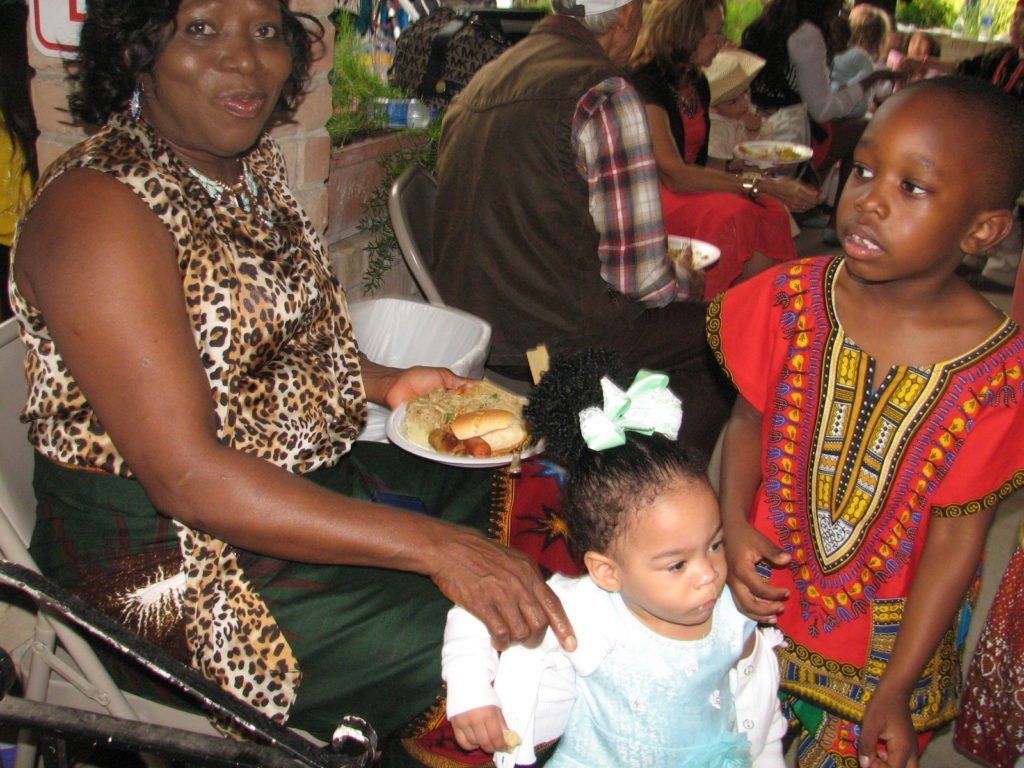 Woman with a leopard-print top serves food to children at an outdoor gathering.