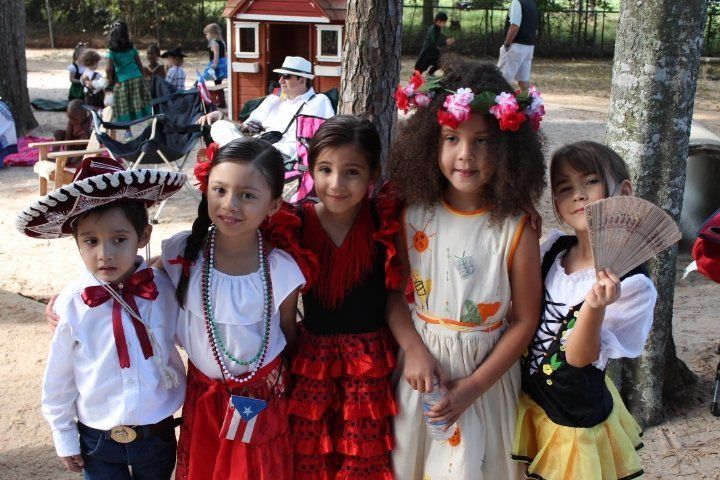 Children in festive costumes at an outdoor event, posing together.