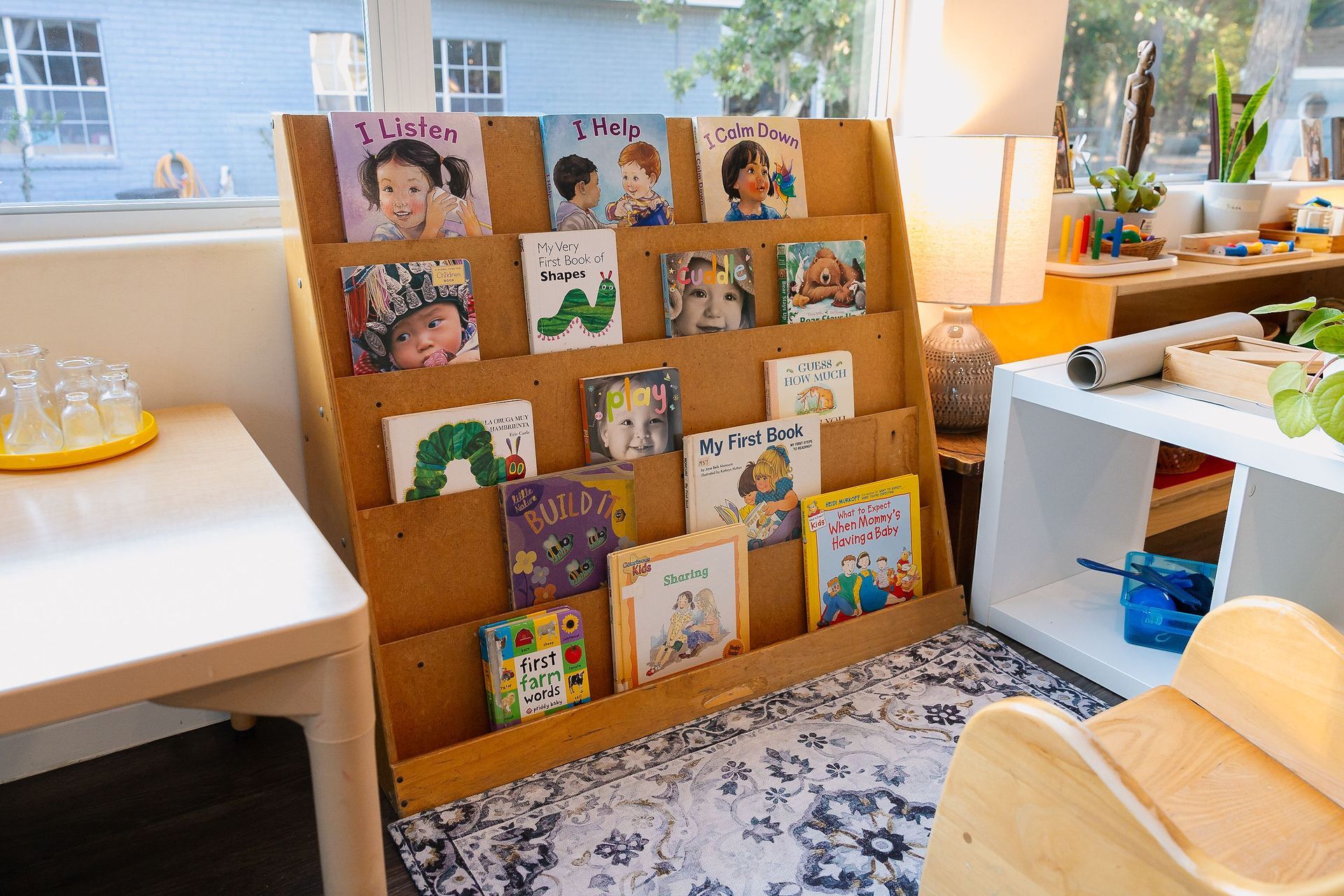Books displayed on a wooden rack in a bright room by a window