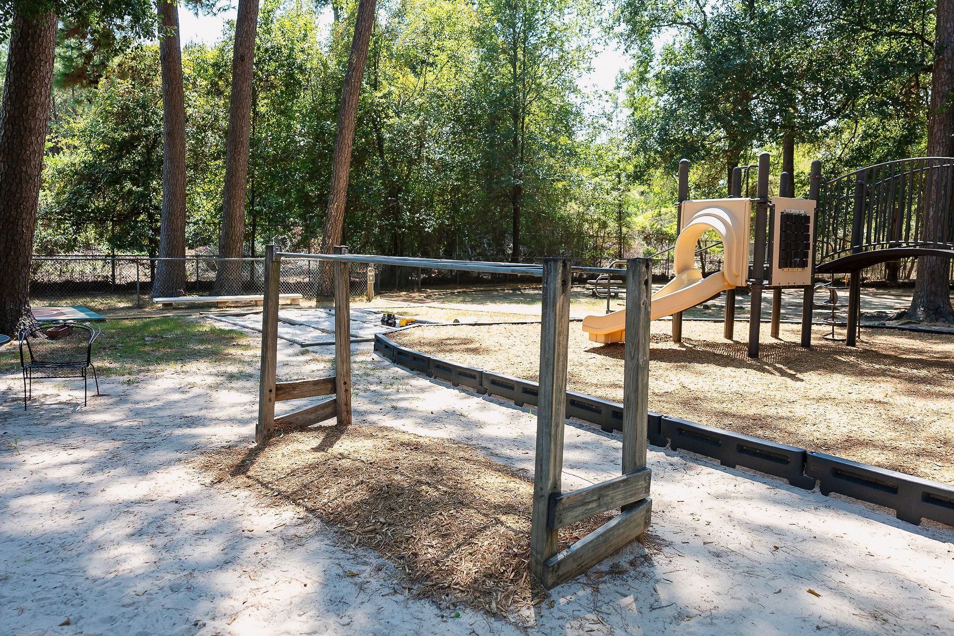 Playground at Northwood Montessori School with monkey bars, slide, and wood chips, surrounded by trees.