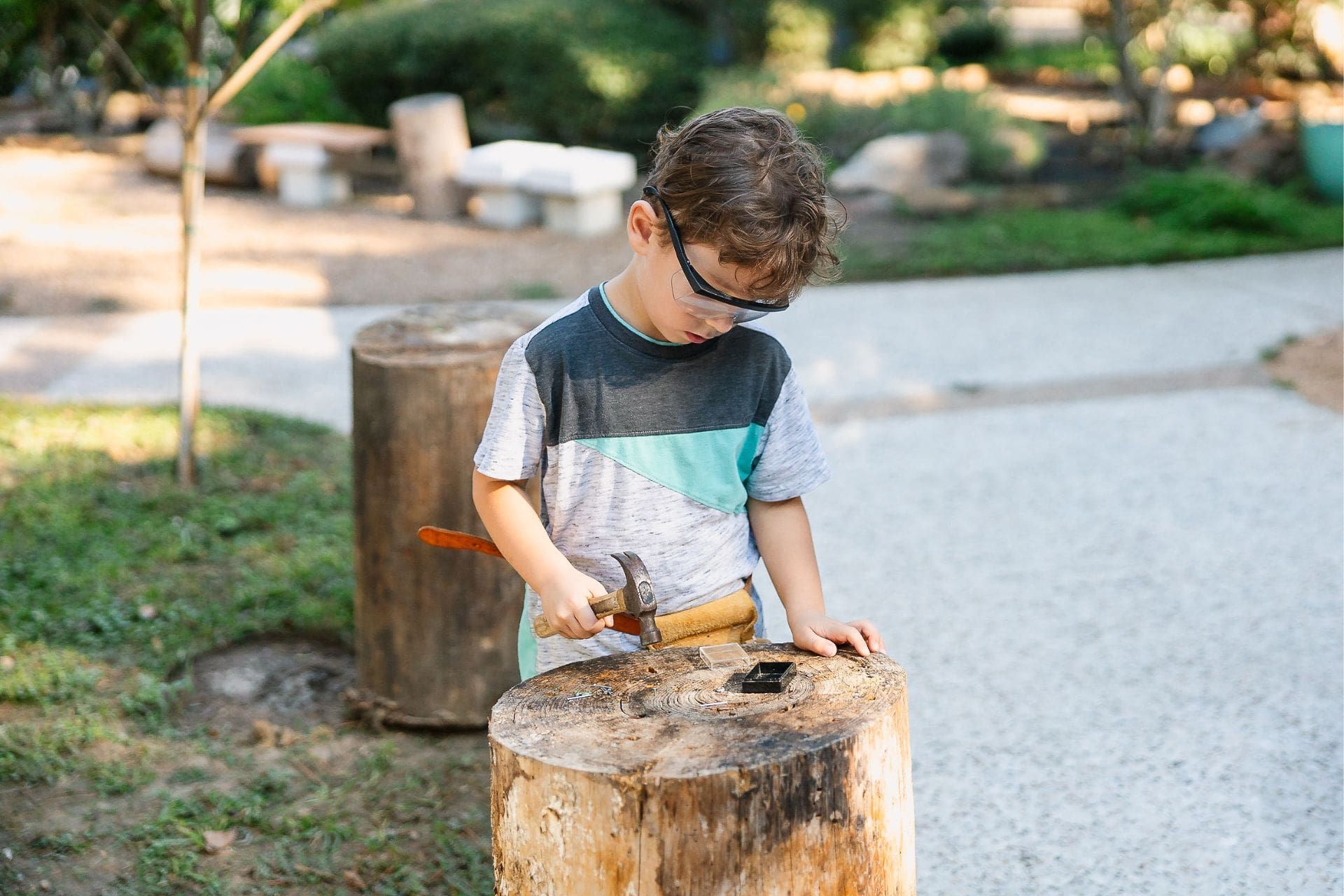 Montessori child hammering wood with focus, showing persistence and independence in work.
