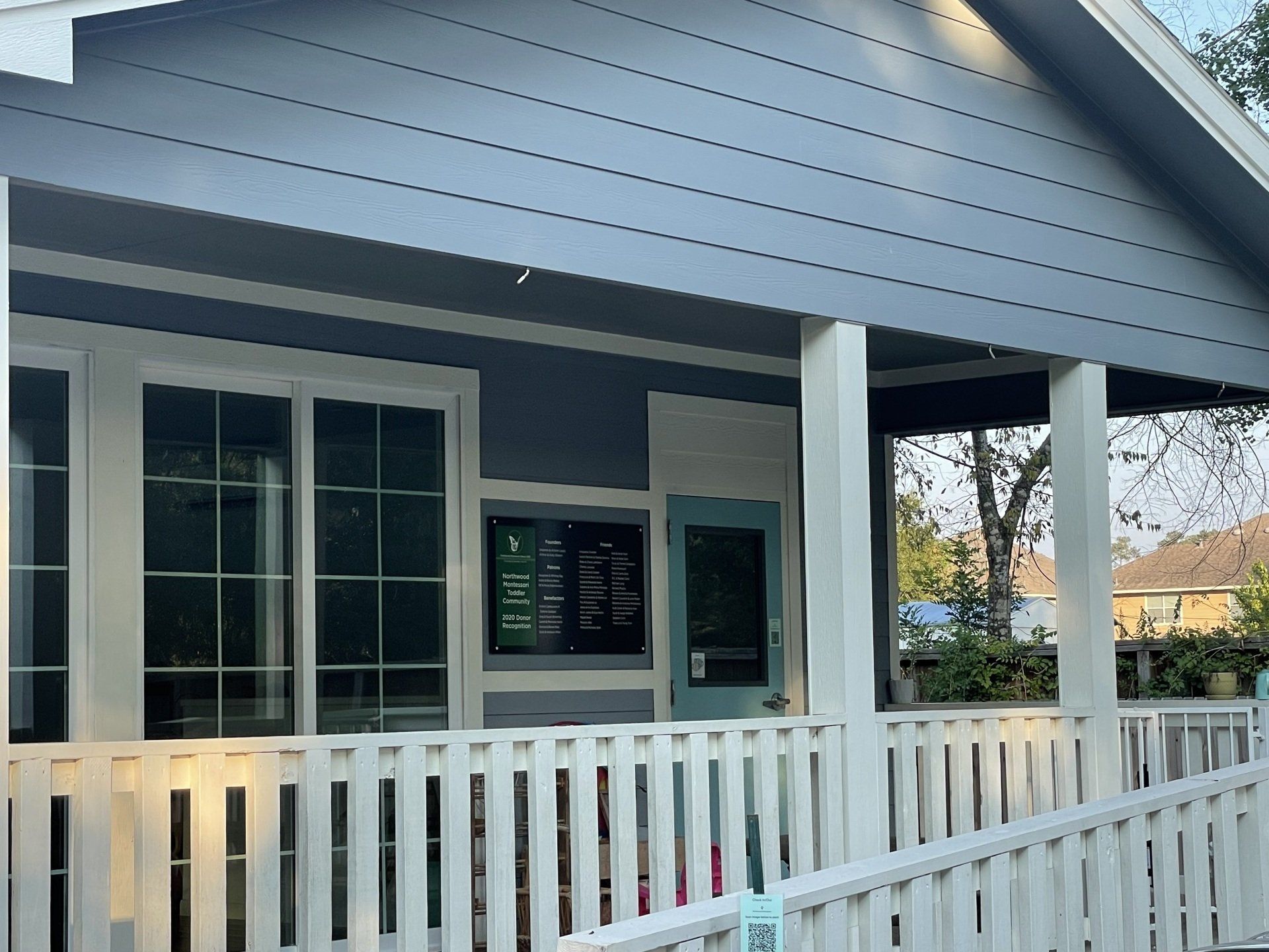 Exterior of Northwood Montessori School with a covered porch, white railing, and blue siding.