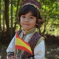 Montessori Young child in ornate costume holding a Spanish flag.