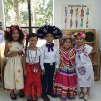 Montessori Children in traditional outfits, smiling, posing in a classroom with cultural displays.