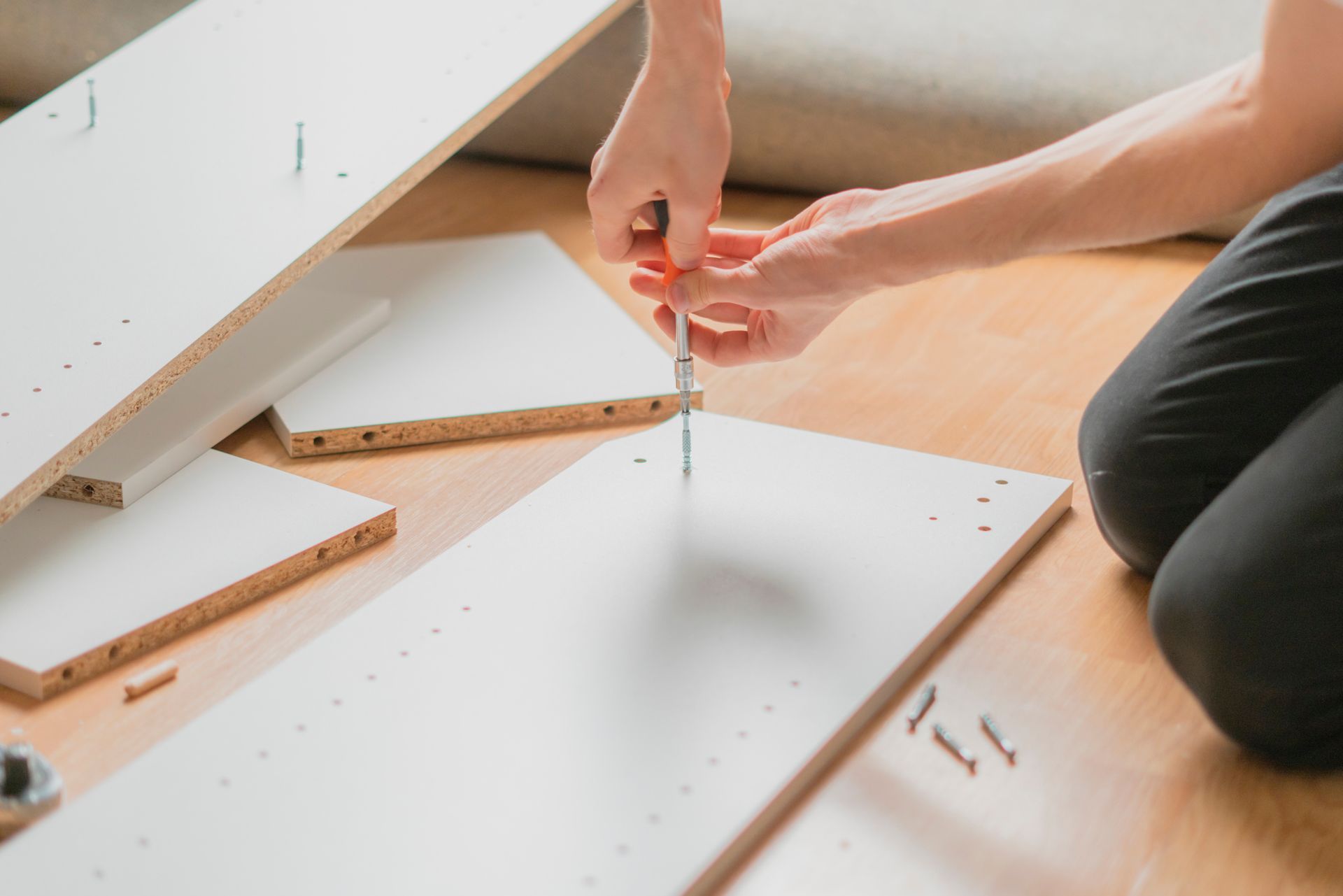 A person is using a screwdriver to assemble a piece of furniture.