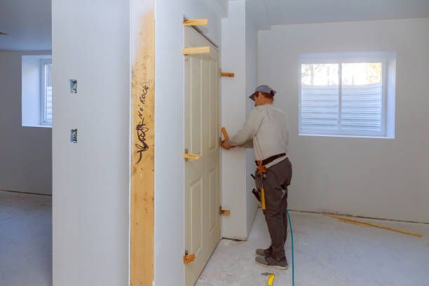 A man is using a hammer to drill a hole in a wall.