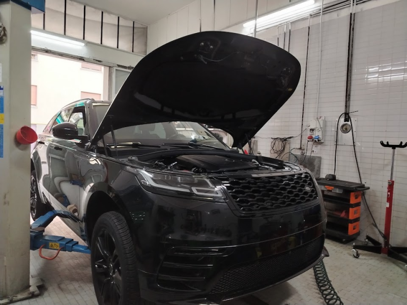 SUV nero in un'officina con il cofano aperto per manutenzione.