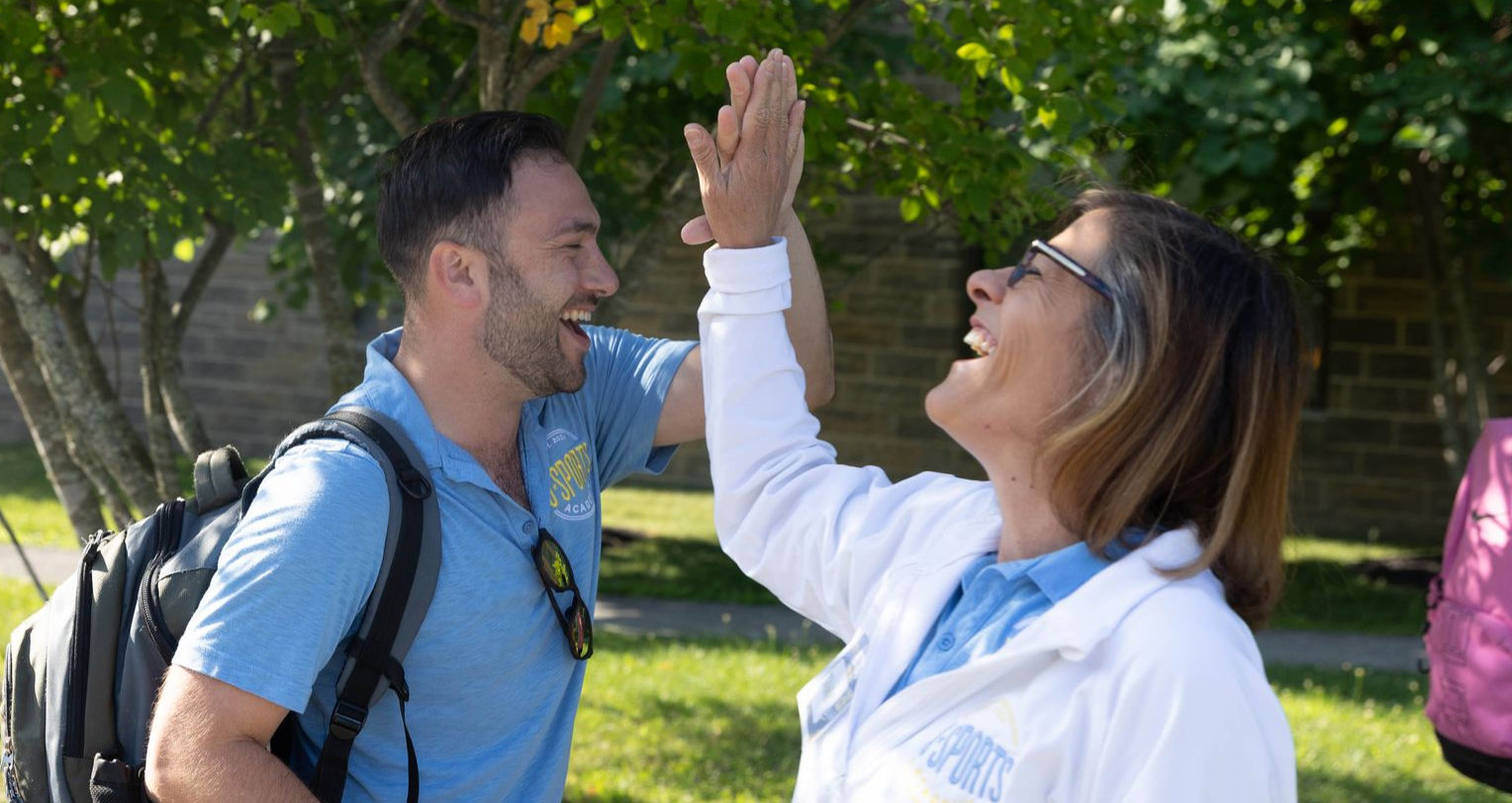 Coach Jason and Coach Tammy giving each other a high five and laughing.