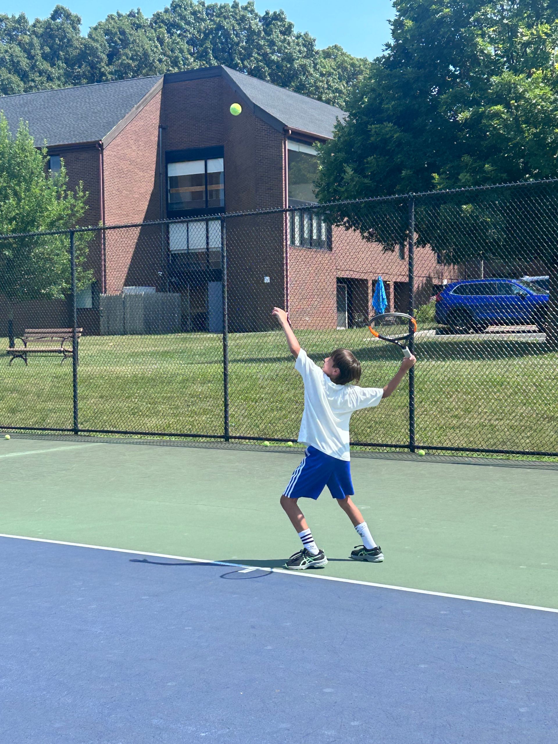 A young boy is playing tennis on a court