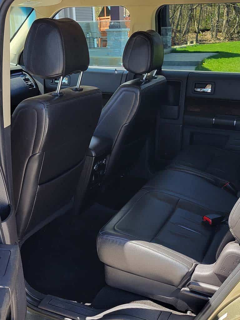 Interior of a vehicle with black leather seats and headrests; the back seats are upright.