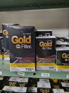 NAPA Gold Filter boxes on a store shelf. Boxes are dark with gold text and red/white lines.