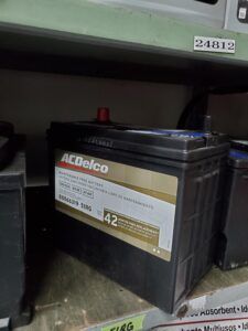 ACDelco car battery on a shelf. Black with gold and white label.