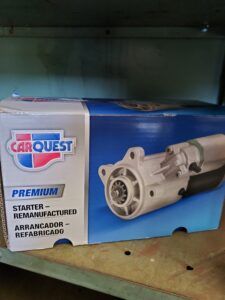 Box of Carquest Premium starter motor, remanufactured. Blue and white box with an image of the starter.