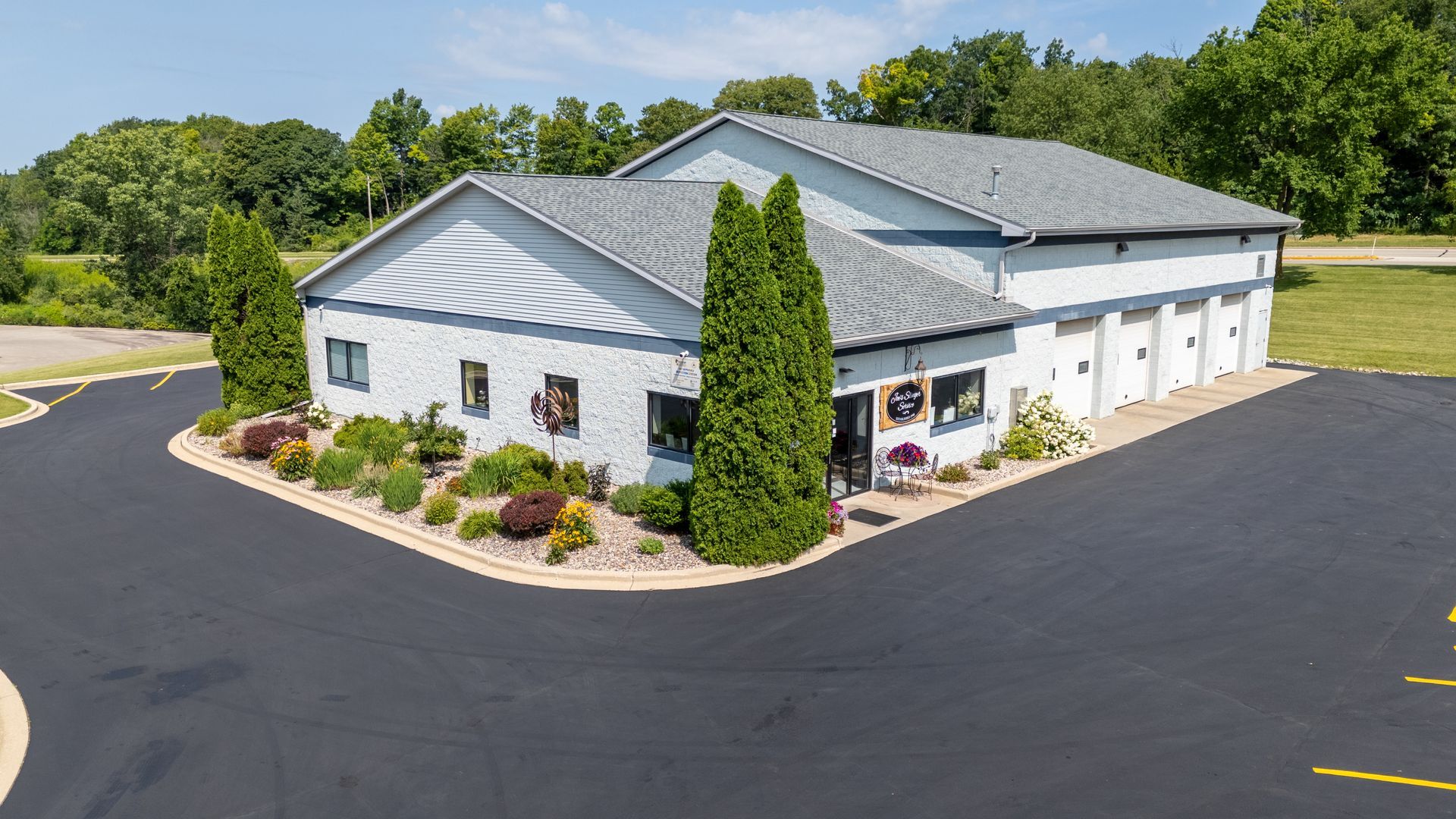 Exterior view of a light blue building with a gray roof and several garage doors | Joe's Slinger Service, LLC