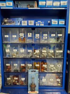 Blue parts organizer filled with small auto light bulbs and boxes of parts.