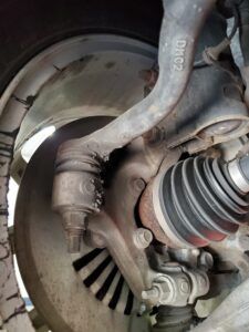 Car suspension components: ball joint, control arm, brake rotor, and CV axle visible.