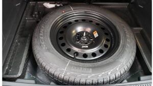 Spare tire in a car's trunk; black tire on a black steel rim.