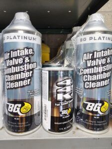 Three cans of BG Platinum Air Intake, Valve & Combustion Chamber Cleaner on a shelf.